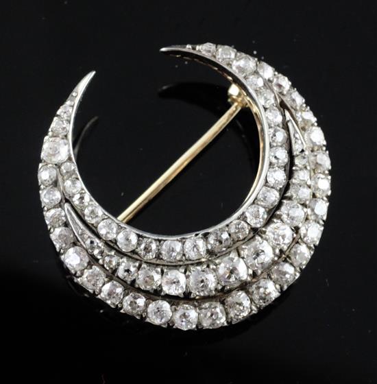 An early 20th century gold and silver, triple row diamond set crescent pendant brooch, 29mm.